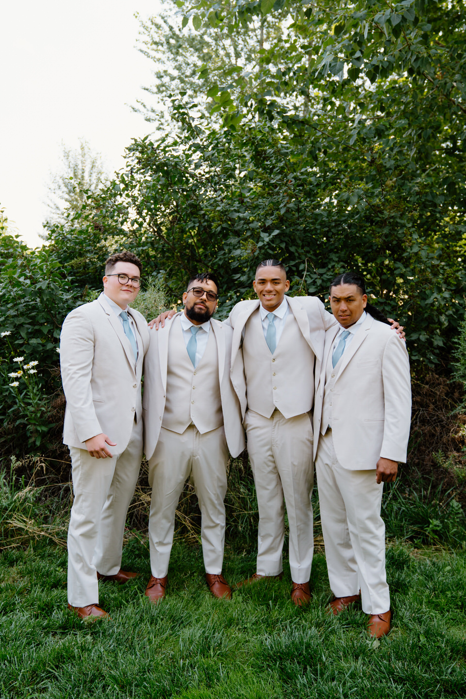 Groom and groomsmen pose casually with arms around each other before wedding at Green Villa Barn and Garden.