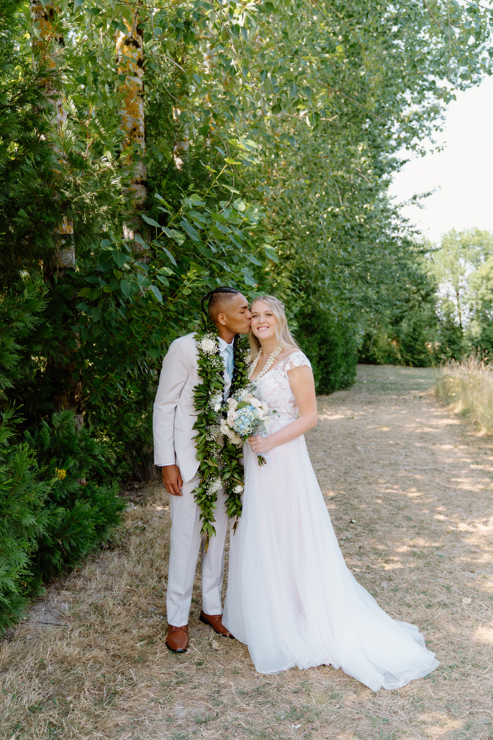 Bride and groom pose together in the garden at Green Villa Barn during their beautiful summer wedding in Oregon.