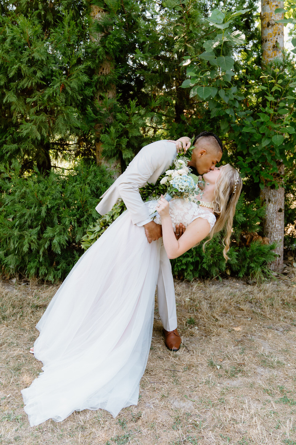 Groom dips the bride as she clutches her hydrangea wedding bouquet.