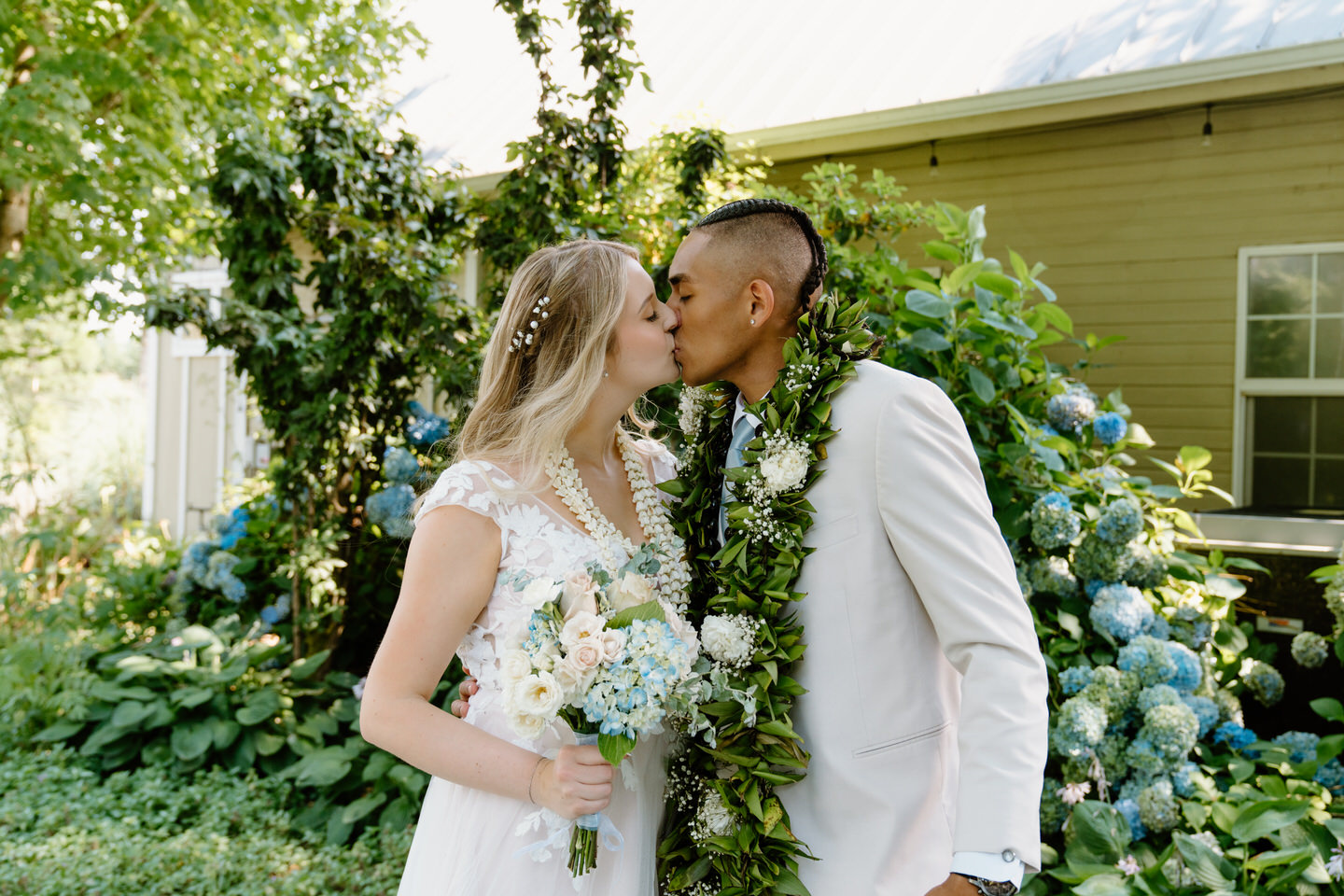 Couple shares a kiss in front of the flowers in the Green Villa Garden