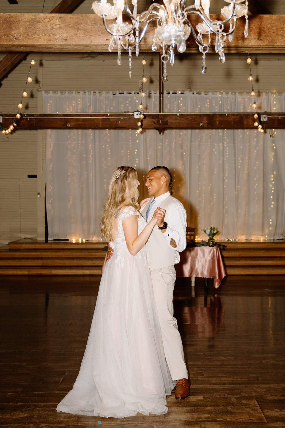 Newlyweds share their first dance under the chandelier of their wedding at Green Villa Barn and Gardens.