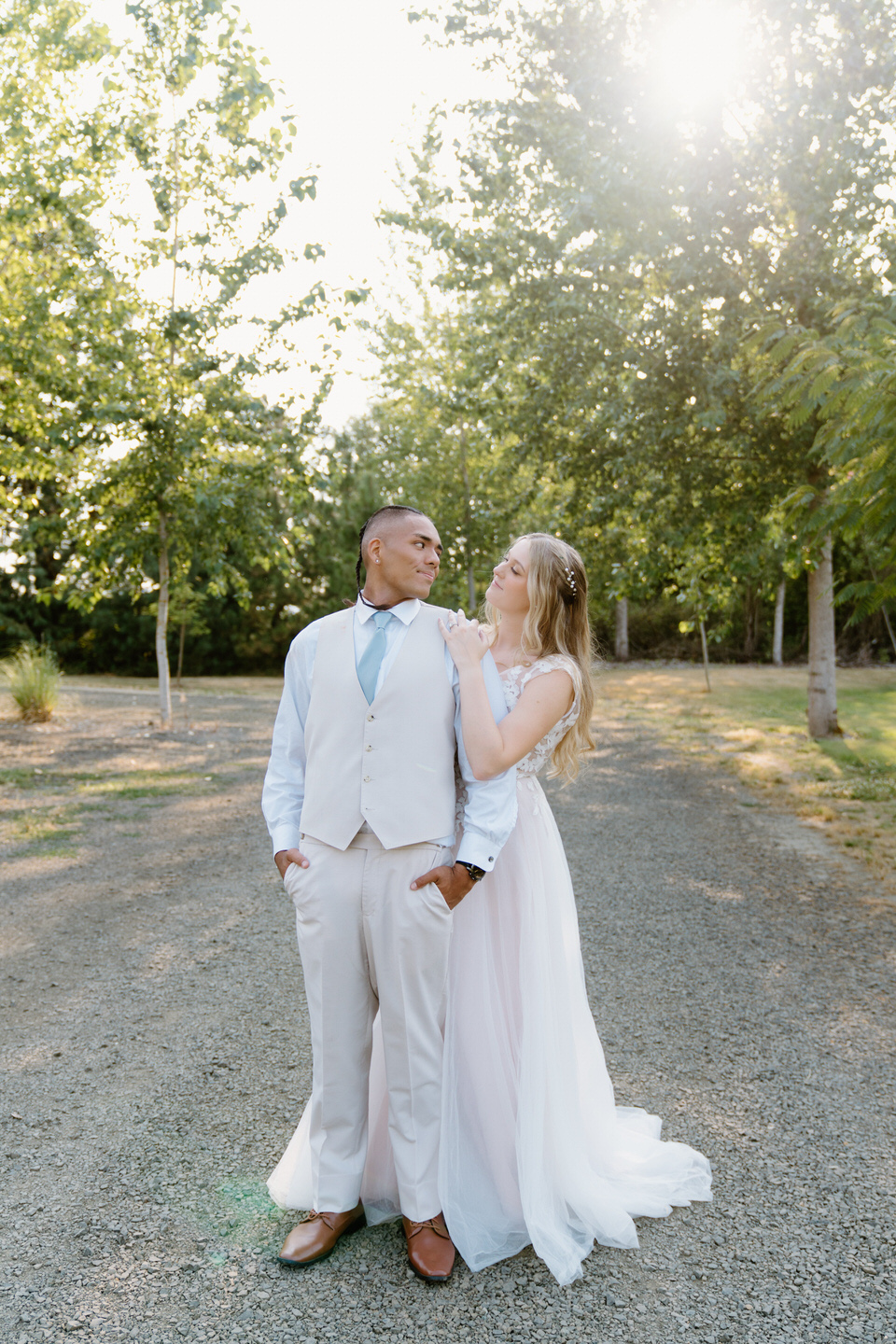 Bride and groom embrace during golden hour, the soft sunlight glowing behind them at their Green Villa Barn wedding.