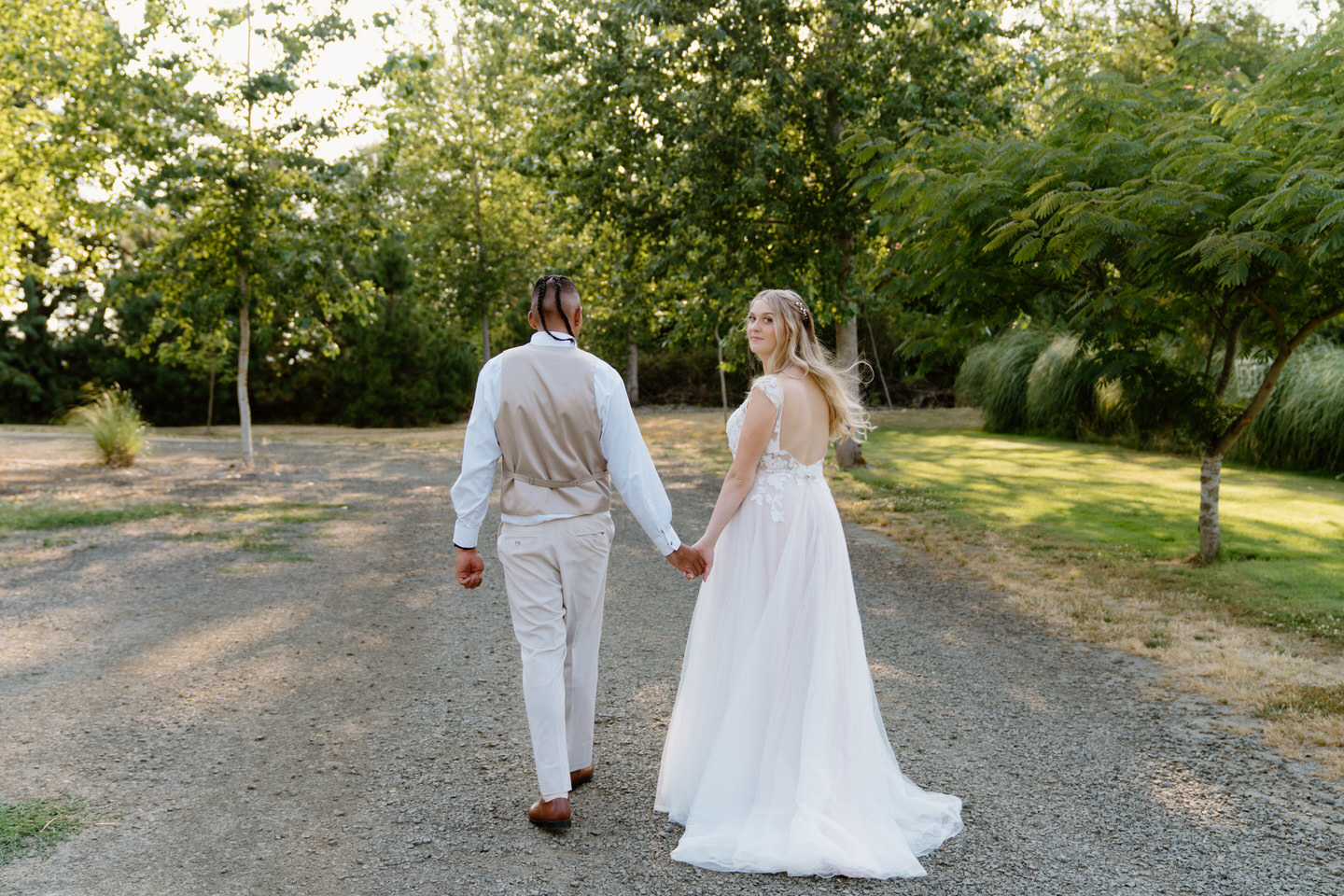 Newlyweds stand hand-in-hand outside Green Villa Barn, surrounded by nature and lush greenery on their wedding day.