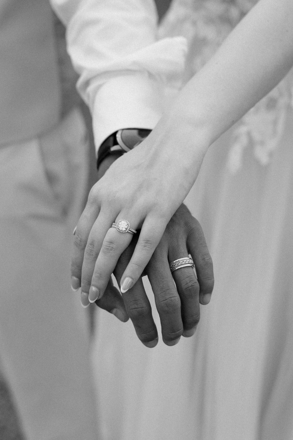 Bride and groom show off their new wedding rings, her hand laying on top of his.