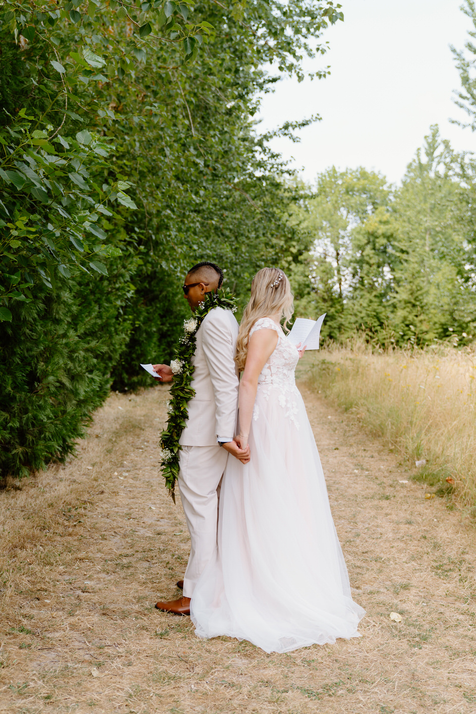 Bride and groom share a first touch, holding hands back-to-back prior to their wedding ceremony.