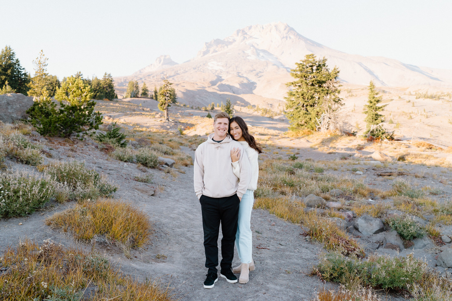 The couple standing on a gravel trail, golden leaves scattered on the ground at Mount Hood.