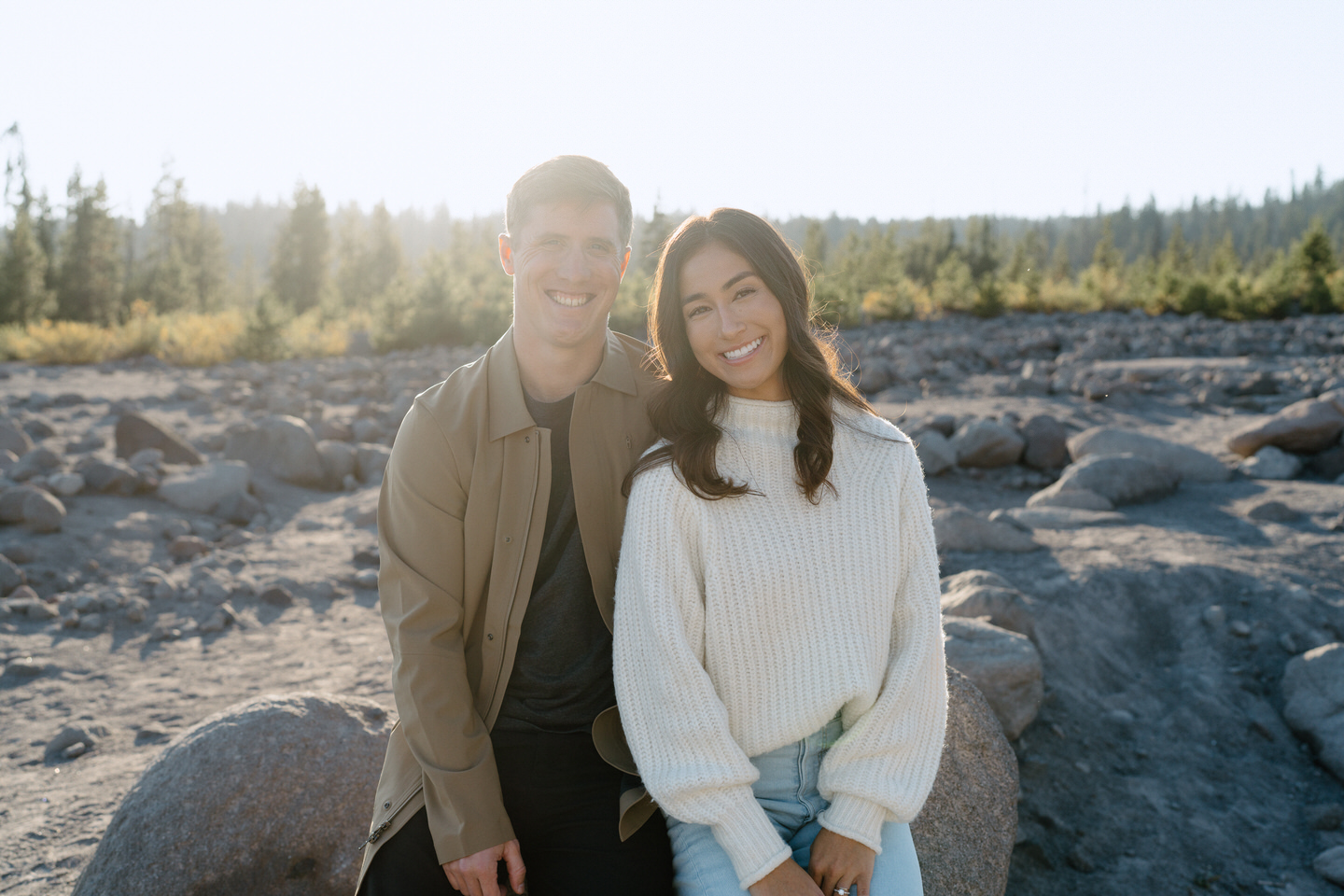 The couple leaning against each other, their neutral outfits blending harmoniously with the subdued tones of the fall landscape at White River West Sno Park.