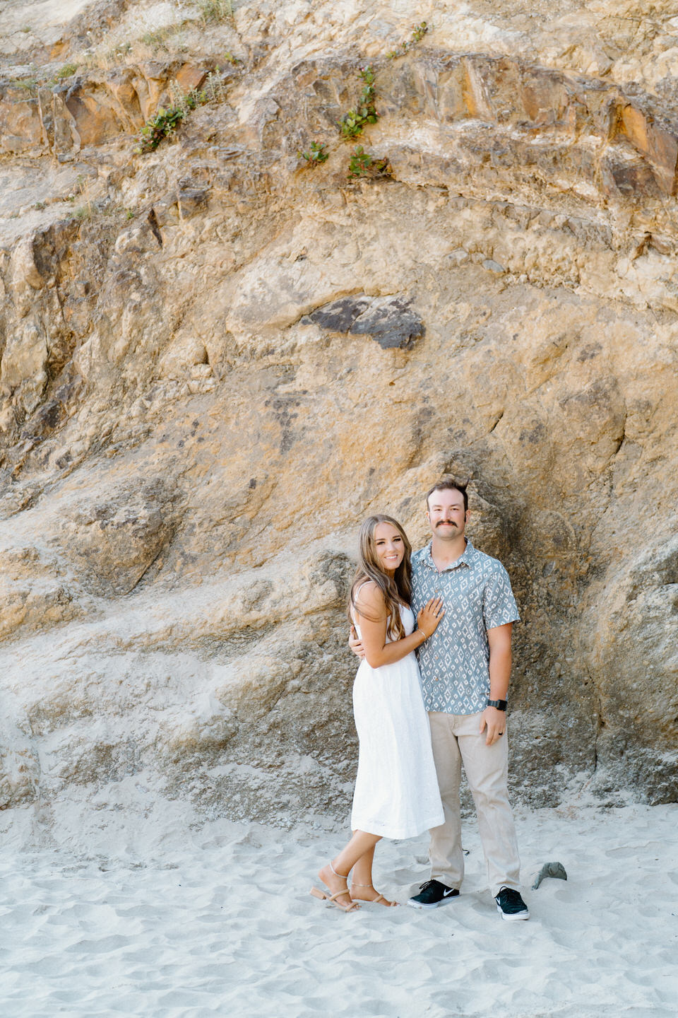 Couple in white and blue outfits in front of cliffs on Oregon coast