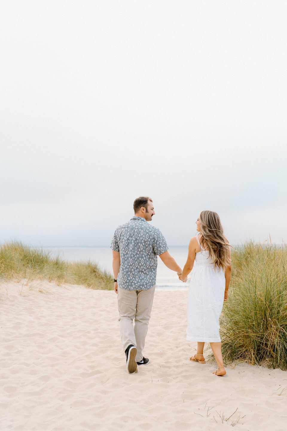 Engaged couple walk on the beach for Oregon coast engagement session