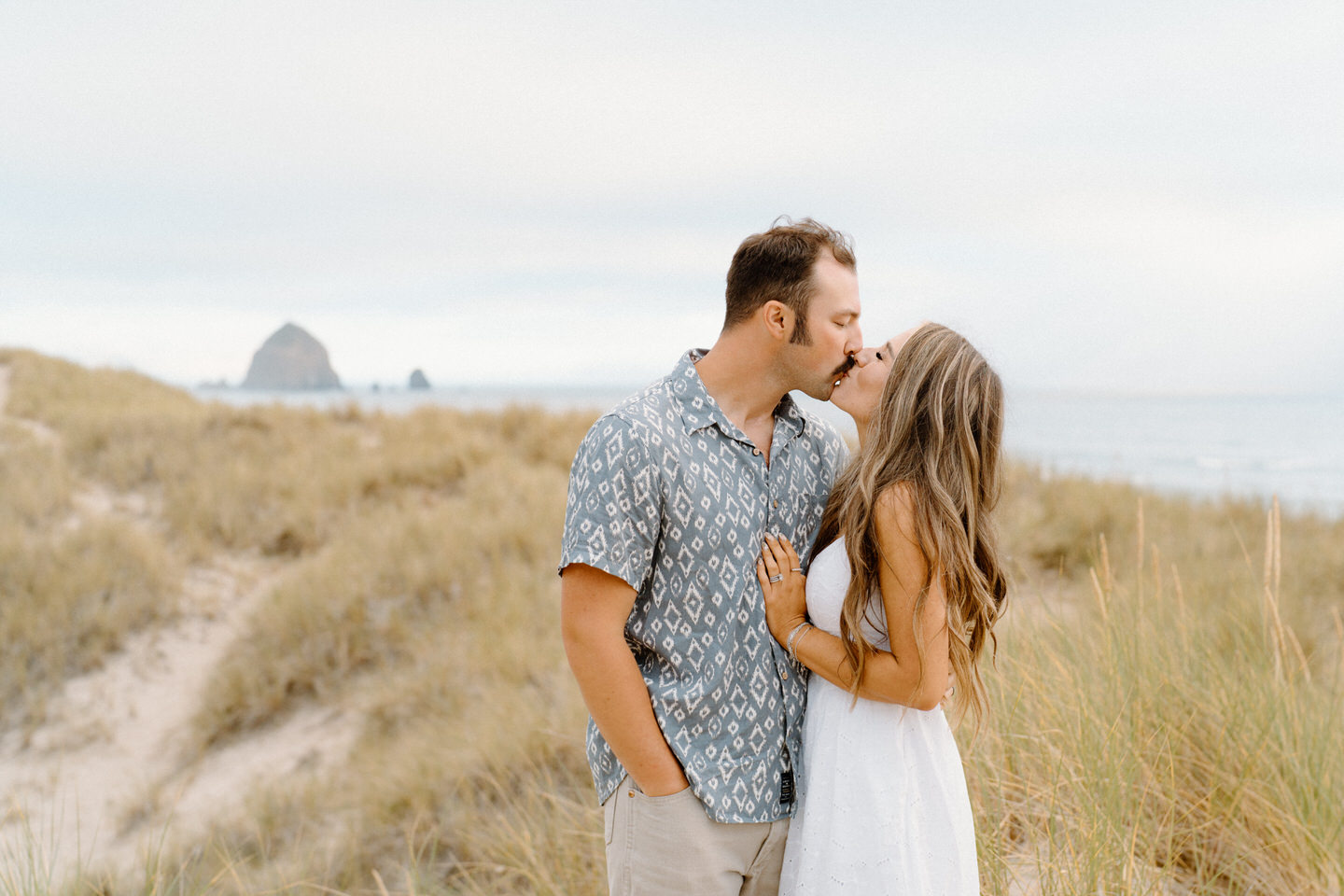 Couple kisses in front of Haystack Rock