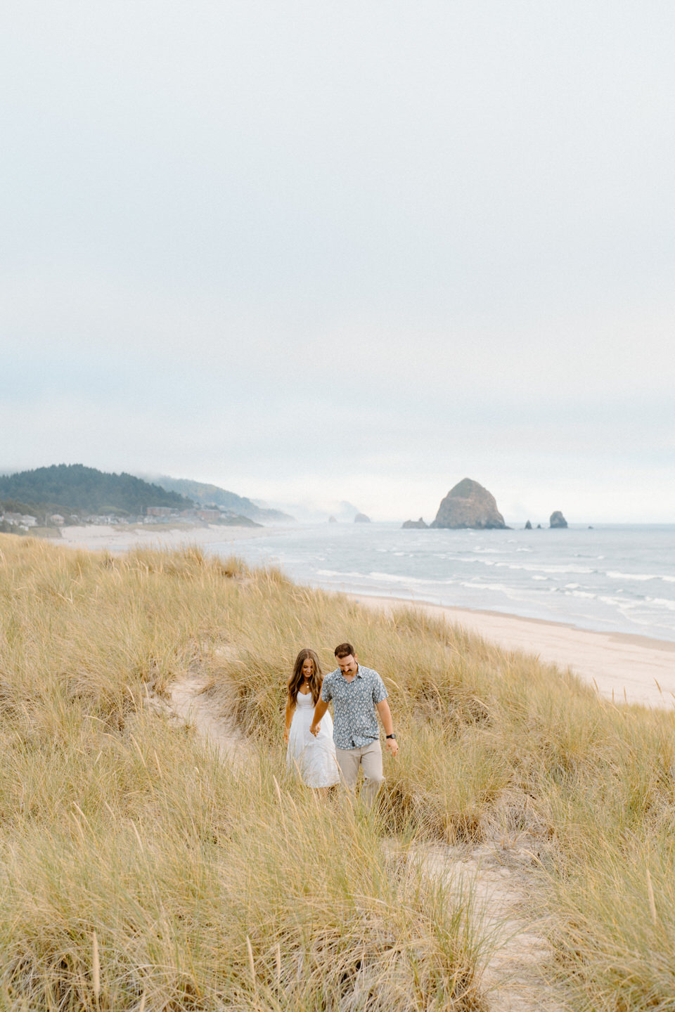 Wide shot of couple walking through beach grass