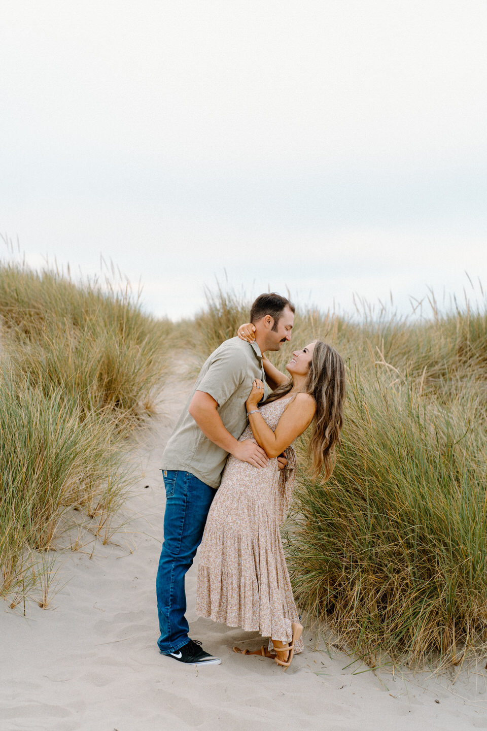 Couple in neutral colors standing in tall grass on the coast