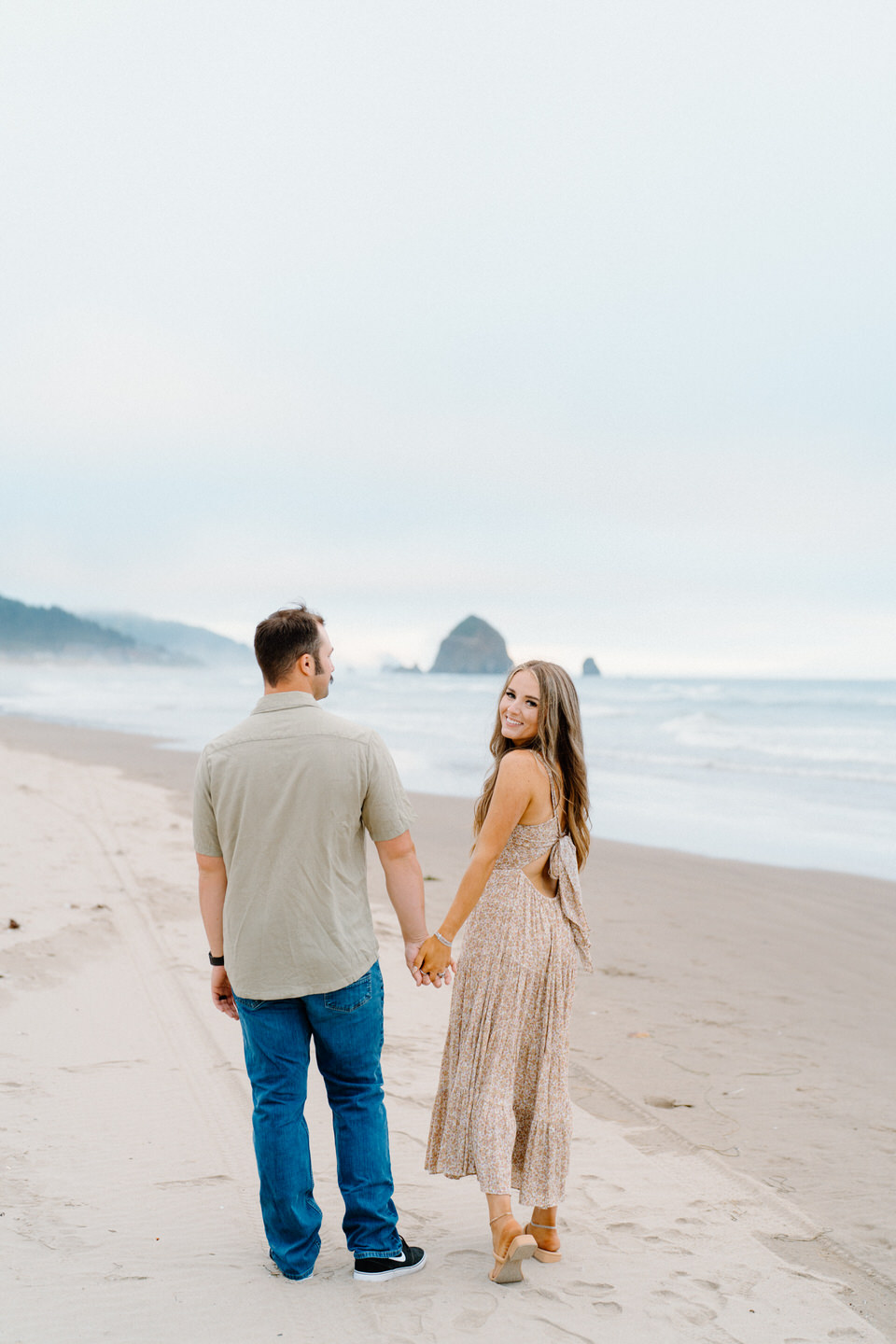 Couple walking on beach with woman looking back