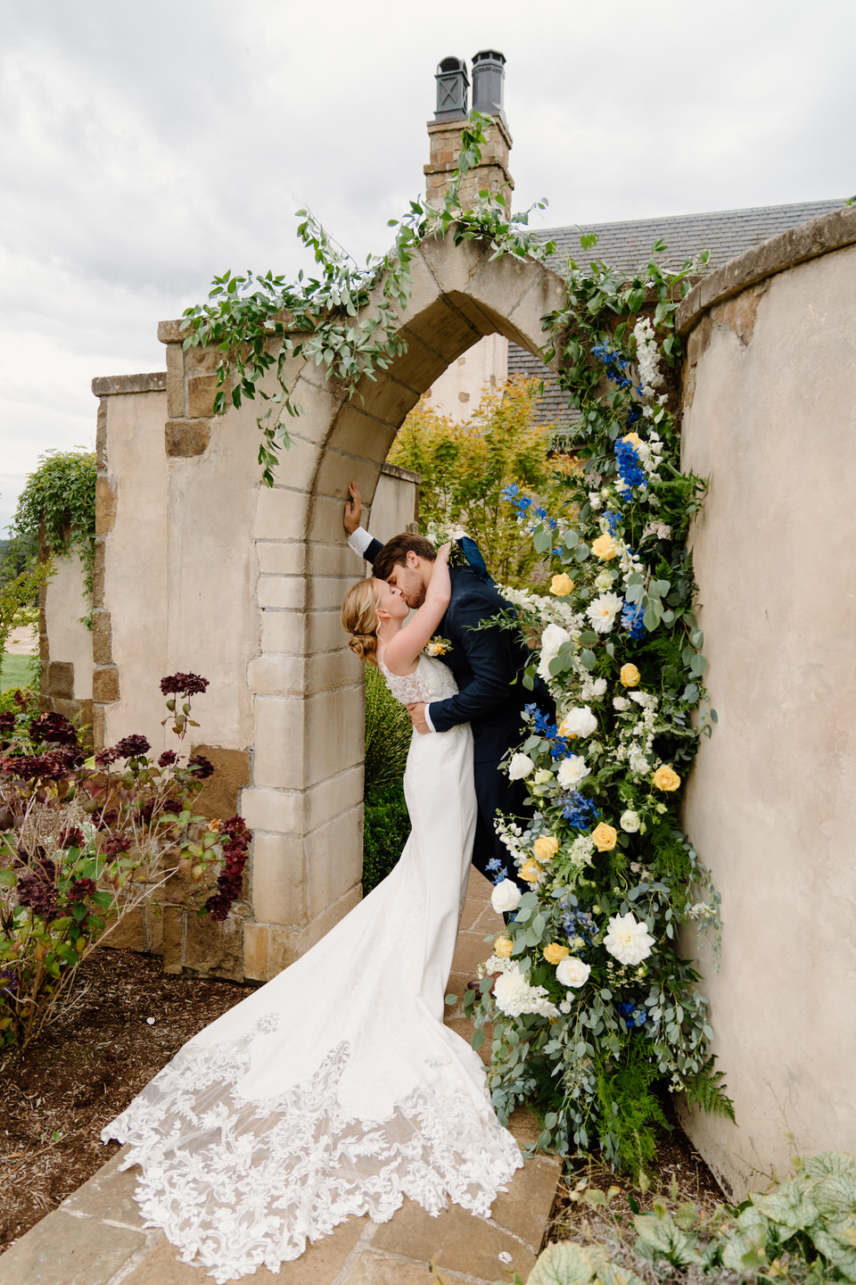 Bride and groom in floral arch with stone features.